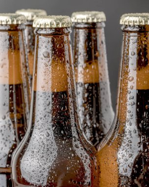 Kahverengi bir şişede soğuk bira ve cam yüzeyinde büyük su damlaları. Kara zanaat birası