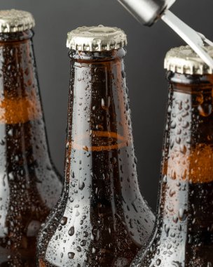 Kahverengi bir şişede soğuk bira ve cam yüzeyinde büyük su damlaları. Kara zanaat birası