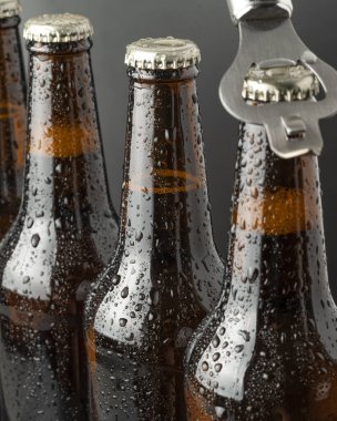 Kahverengi bir şişede soğuk bira ve cam yüzeyinde büyük su damlaları. Kara zanaat birası