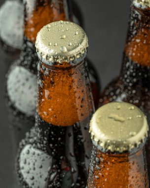 Kahverengi bir şişede soğuk bira ve cam yüzeyinde büyük su damlaları. Kara zanaat birası