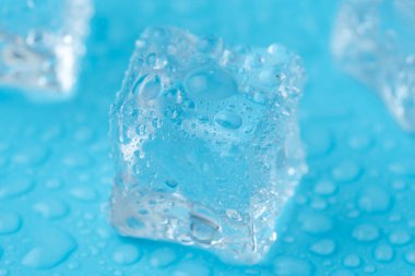 Mavi zemin üzerinde su damlaları olan buz ve buz parçaları. Soğuk ve tazelik kavramı