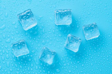 Mavi zemin üzerinde su damlaları olan buz ve buz parçaları. Soğuk ve tazelik kavramı