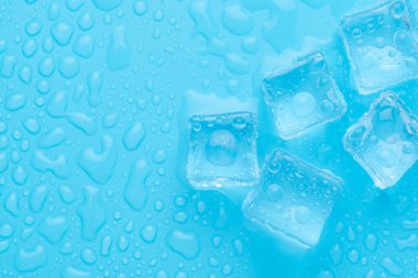 Mavi zemin üzerinde su damlaları olan buz ve buz parçaları. Soğuk ve tazelik kavramı