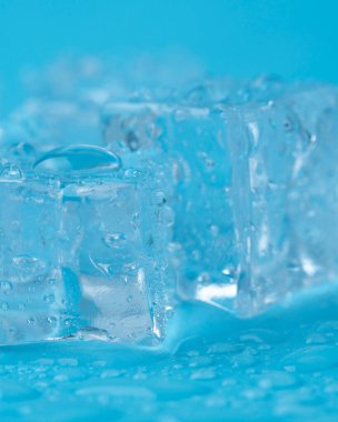 Mavi zemin üzerinde su damlaları olan buz ve buz parçaları. Soğuk ve tazelik kavramı