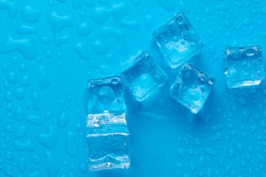 Mavi zemin üzerinde su damlaları olan buz ve buz parçaları. Soğuk ve tazelik kavramı