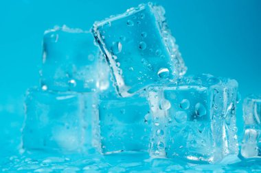 Mavi zemin üzerinde su damlaları olan buz ve buz parçaları. Soğuk ve tazelik kavramı