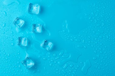 Mavi zemin üzerinde su damlaları olan buz ve buz parçaları. Soğuk ve tazelik kavramı
