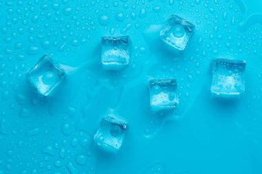 Mavi zemin üzerinde su damlaları olan buz ve buz parçaları. Soğuk ve tazelik kavramı