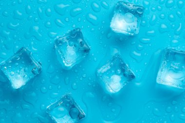 Mavi zemin üzerinde su damlaları olan buz ve buz parçaları. Soğuk ve tazelik kavramı