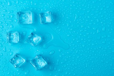 Mavi zemin üzerinde su damlaları olan buz ve buz parçaları. Soğuk ve tazelik kavramı