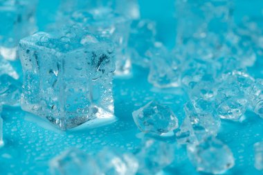 Mavi zemin üzerinde su damlaları olan buz ve buz parçaları. Soğuk ve tazelik kavramı