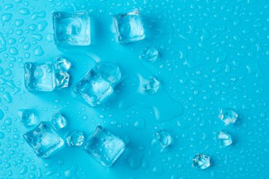 Mavi zemin üzerinde su damlaları olan buz ve buz parçaları. Soğuk ve tazelik kavramı