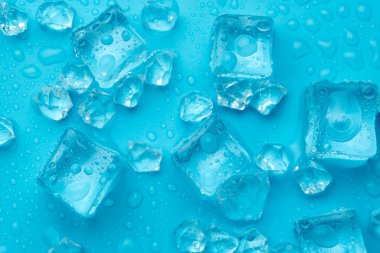 Mavi zemin üzerinde su damlaları olan buz ve buz parçaları. Soğuk ve tazelik kavramı