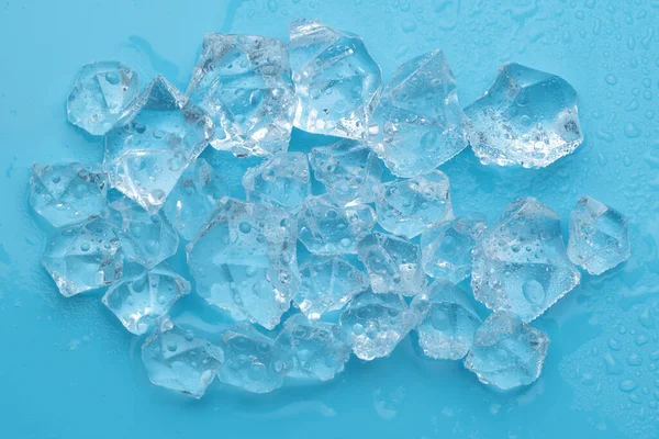 Ice cubes and ice shards with water drops on a blue background. The concept of cold and freshness