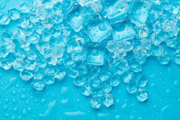 Ice cubes and ice shards with water drops on a blue background. The concept of cold and freshness