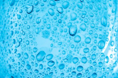 Su damlaları mavi arka planda, yakın planda.