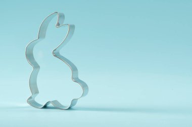 Easter bunny on blue background. Happy Easter Day concept. Minimal Easter concept. Space for text. Easter Cookie Cutter on baking background.