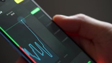 Buying stocks in the investment market in close-up. Checking data in the financial market. Using your phone to analyze a rising stock fund. Displaying a stock market chart on a touch screen monitor.