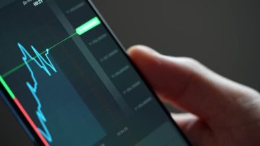 Buying stocks in the investment market in close-up. Checking data in the financial market. Using your phone to analyze a rising stock fund. Displaying a stock market chart on a touch screen monitor.