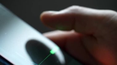 Buying stocks in the investment market in close-up. Checking data in the financial market. Using your phone to analyze a rising stock fund. Displaying a stock market chart on a touch screen monitor.