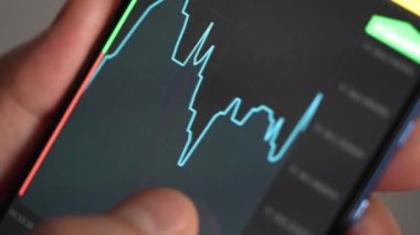 Buying stocks in the investment market in close-up. Checking data in the financial market. Using your phone to analyze a rising stock fund. Displaying a stock market chart on a touch screen monitor.