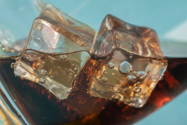 Coke or club soda poured into a glass with ice cubes