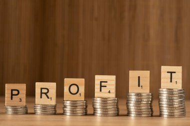 Finance, dice lettering, word PROFIT on wooden texture dice on wooden background. Concept in finance and business