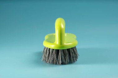 Hand in yellow rubber glove holds sponge for washing dishes and cleaning, hand clenches sponge into fist on blue background