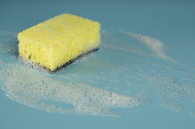 Multicolored sponges for washing dishes and other household needs. The sponges lie on a blue background at a slight angle. Cleaning and Dishwashing Concept