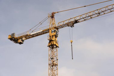 Crane and construction site against the blue sky. Working on large construction sites, and many cranes working in the new construction business.