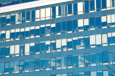 Modern office building facade. Tall business center with a glass facade. Construction of a glass facade structure. The glare of the sun on the glass wall of a skyscraper