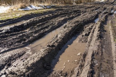 Kirli, geçilemez yol. Sonbahar ormanında off-road pisti. Buzlu sonbahar yolundaki derin rutubetler. Yağmurlu bir günde ıslak, çamurlu kırsal yol Bahar dağlarında kırsal yol çamurlu su birikintileriyle dolu