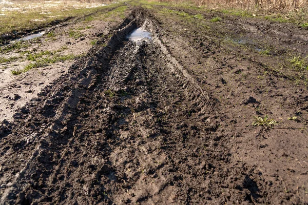 stock image Dirty impassable road. Off-road track in the autumn forest. Deep ruts on a slushy autumn road. Wet muddy countryside road on a rainy day Broken country road in spring mountains with many muddy puddles