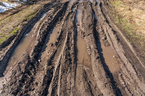 Kirli, geçilemez yol. Sonbahar ormanında off-road pisti. Buzlu sonbahar yolundaki derin rutubetler. Yağmurlu bir günde ıslak, çamurlu kırsal yol Bahar dağlarında kırsal yol çamurlu su birikintileriyle dolu