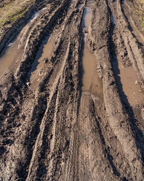 stock image Dirty impassable road. Off-road track in the autumn forest. Deep ruts on a slushy autumn road. Wet muddy countryside road on a rainy day Broken country road in spring mountains with many muddy puddles