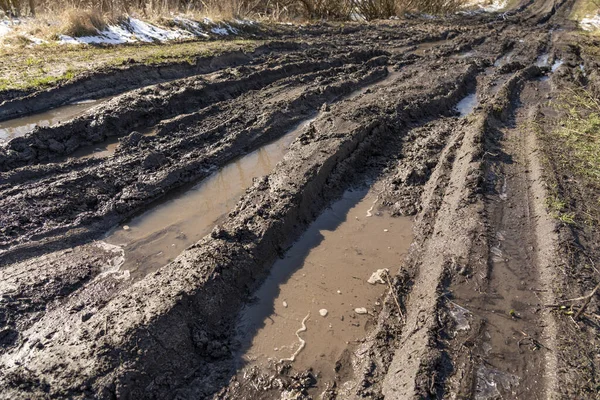 Kirli, geçilemez yol. Sonbahar ormanında off-road pisti. Buzlu sonbahar yolundaki derin rutubetler. Yağmurlu bir günde ıslak, çamurlu kırsal yol Bahar dağlarında kırsal yol çamurlu su birikintileriyle dolu