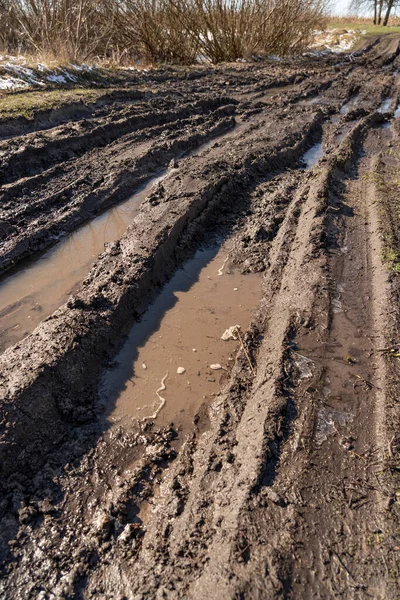 Kirli, geçilemez yol. Sonbahar ormanında off-road pisti. Buzlu sonbahar yolundaki derin rutubetler. Yağmurlu bir günde ıslak, çamurlu kırsal yol Bahar dağlarında kırsal yol çamurlu su birikintileriyle dolu