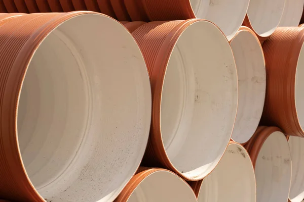 Orange plastic pipes used on a construction site. Orange PVC sewer pipe for outdoor use. Stacked in a row premium plastic pipes for wastewater