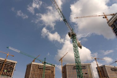 İnşaat alanı ve şehir arka planında kule vinçleri