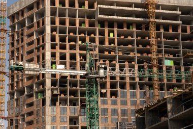 İnşaat alanı ve şehir arka planında kule vinçleri