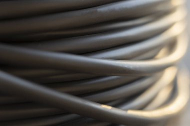 Bir rulo içinde elektrikli siyah kablo. Ağ bağlantısı, bilgisayar kablosu, kablo makarası, veri iletimi. Açık hava fabrikası deposundaki kablo makarasının silüeti.