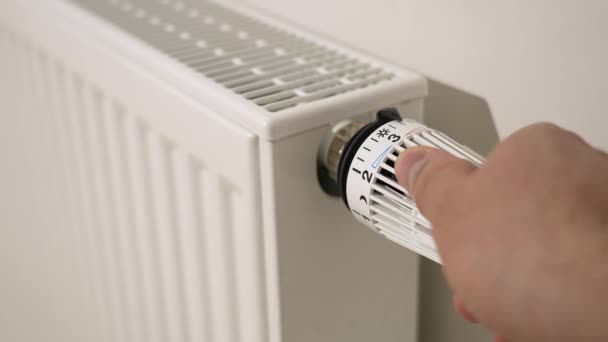 男性は サーモスタットラジエーターバルブ制御を最小設定に設定することで 加熱をオフにします エネルギー危機の間にアパートの暖房をオフにします 省エネ — ストック動画
