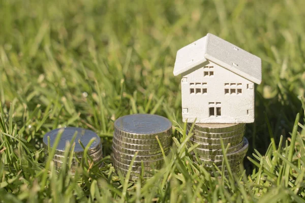 Stacks of coins on the lawn with house house, saving money to buy a house, financial plan mortgage loan concept.