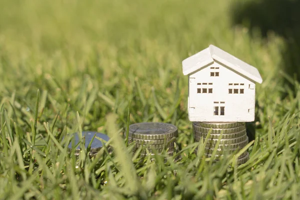 Stacks of coins on the lawn with house house, saving money to buy a house, financial plan mortgage loan concept.