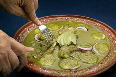  Tipik Meksika yemeği olan nobre aguachile, yeşil sos üzerine yeşil karides ile süslenmiş mor soğan ve taze yeşil avokado dilimleri, mavi bir masada kil bir tabakta servis edilir..