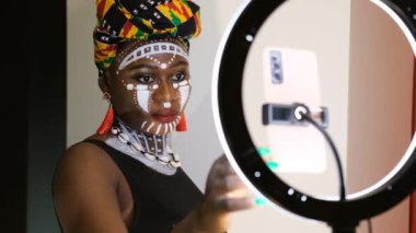 Cep telefonu ve tripodla sosyal medya üzerinde çalışan Afrikalı kadın