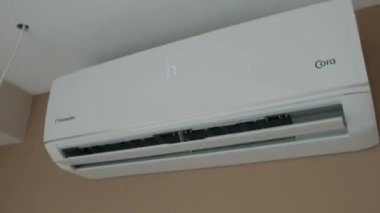 Close Up shot. indoor unit of the air conditioner is attached to wall. Modern air cooling technologies. Turns on, the wing goes down, blinds are opened, drives cold air. Video footage 4k. White design