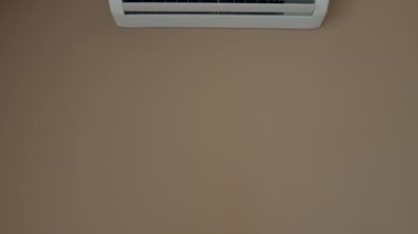 Close Up shot. indoor unit of the air conditioner is attached to wall. Modern air cooling technologies. Turns on, the wing goes down, blinds are opened, drives cold air. Video footage 4k. White design