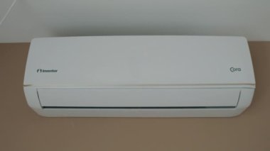 Close Up shot. indoor unit of the air conditioner is attached to wall. Modern air cooling technologies. Turns on, the wing goes down, blinds are opened, drives cold air. Video footage 4k. White design