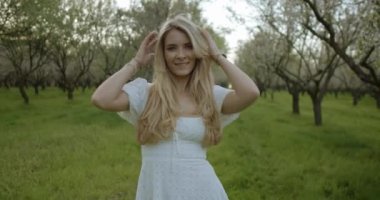 Güzel, genç bir kadın geniş bir alanda gülümsüyor. Resmedilmeye değer bir meyve bahçesinde doğanın tadını çıkarıyor. Saf neşe yakalıyor.